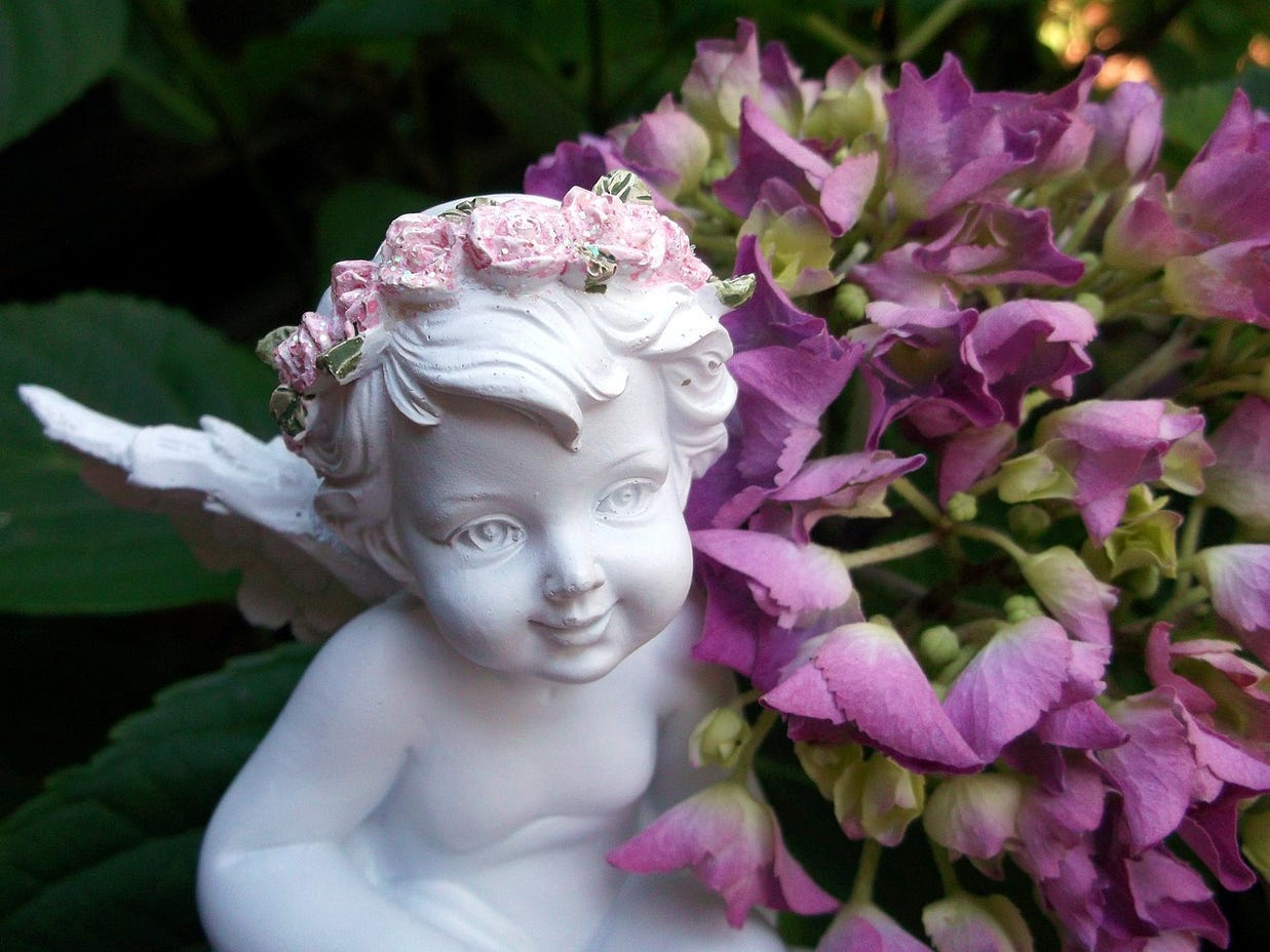 White marble cherub with purple flowers all around