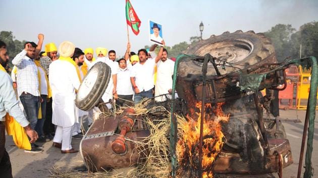 Punjab Youth Congress Workers raise slogans around a tractor set aflame in protest against farm bills at India Gate in New Delhi on Monday.(HT Photo)