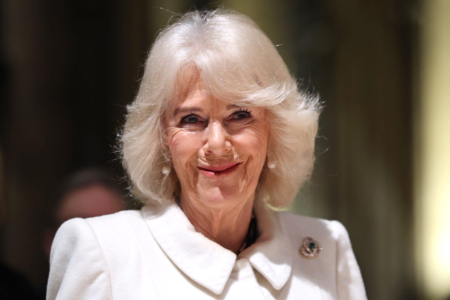 Queen Camilla in white and smiling