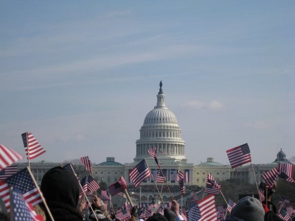 A crowd waving American flags in front of the U.S. Capital.