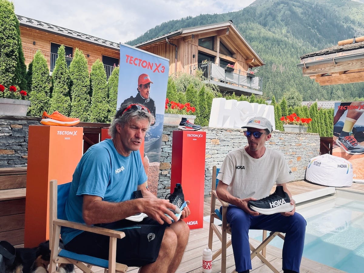 Christophe Aubonnet and Jim Walmsley sitting on camping chairs in front of a cardboard filled with shoes