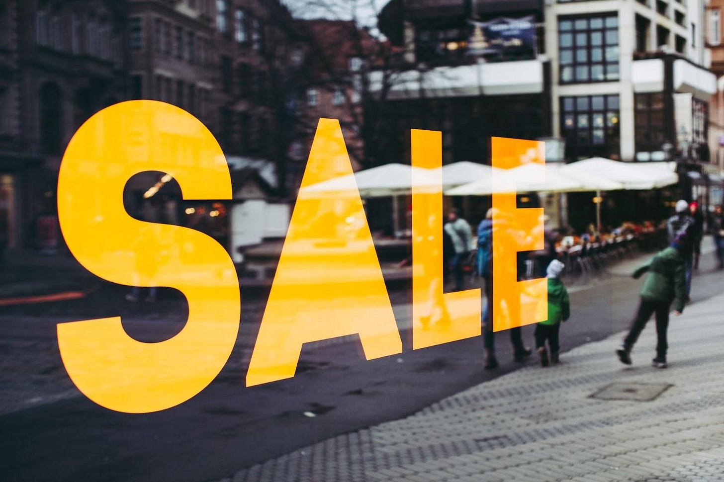 A large sale sign painted on a storefront window in a downtown area. A large sale sign painted on a storefront window in a downtown area.