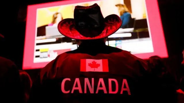 A supporter of Canada's Prime Minister Mark Carney wears a jacket adorned with the Canada flag an d wears a cowboy hat at the Liberal Party election night headquarters in Ottawa