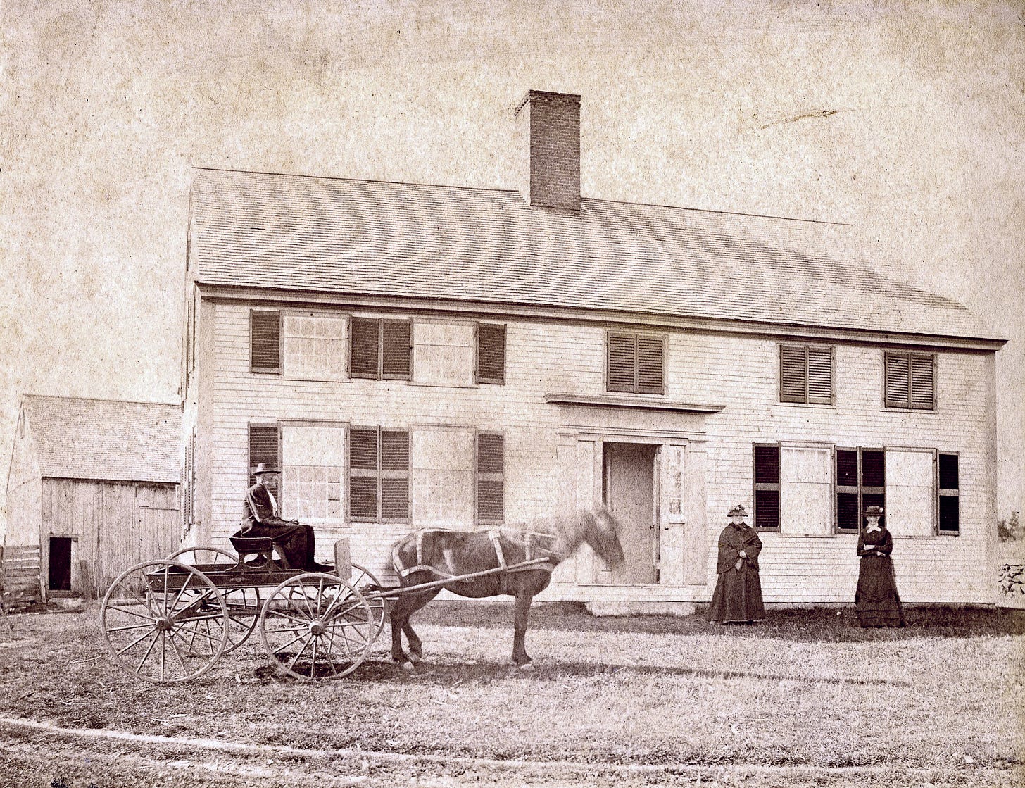 Man on horse drawn cart and two women in front of house