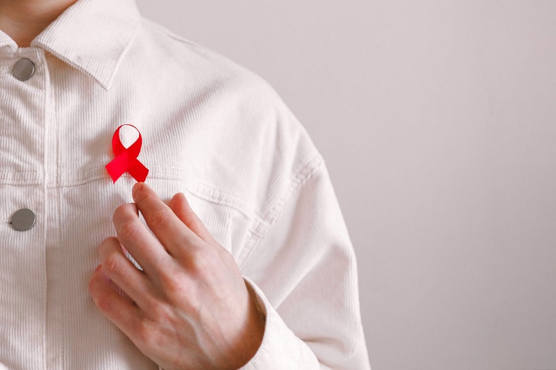 Free Close-up of a red ribbon on a white shirt symbolizing AIDS awareness and support. Stock Photo