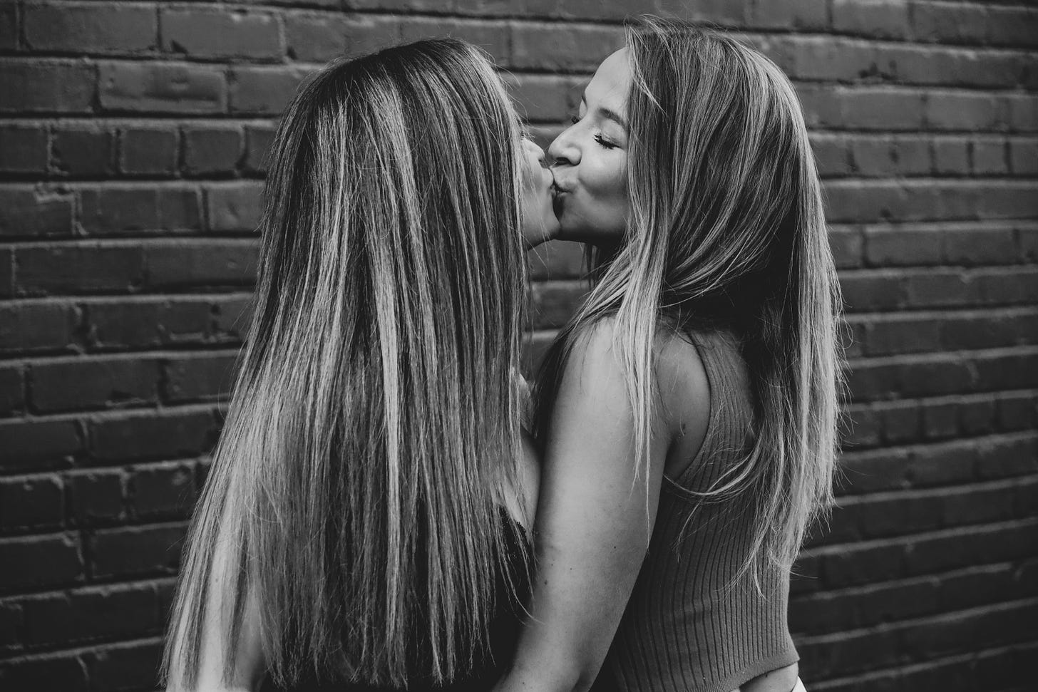 Two long-haired women kissing.