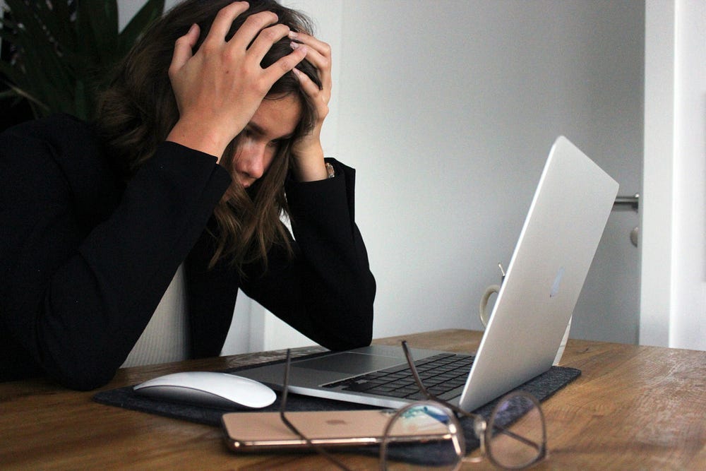 Frustrated woman with her hands on her head starring at a computer screen