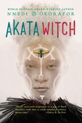 Akata Witch cover; glowy tint; African Albino girl staring straight blue wasp on her forehead and white markings on her face.