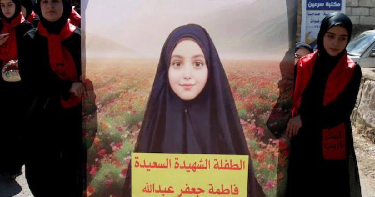 Photo of a banner bearing the face of a girl killed in the exploding pagers incident, carried by other girls at her funeral procession.