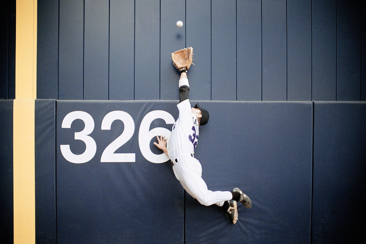 An outfielder reaches for a fly ball.
