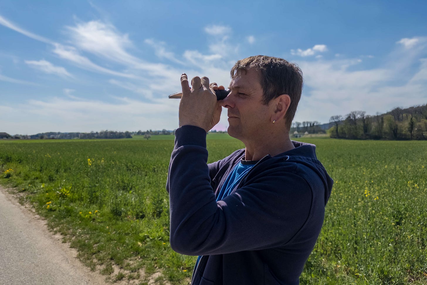 Gerhard Weisshäupl misst mit einem Refraktometer den Brix-Wert eines jungen Rapsfeldes, das sich hinter ihm in der Frühlingslandschaft erstreckt – eine Methode zur Bestimmung der Pflanzengesundheit in der regenerativen Landwirtschaft. Gerhard Weisshäupl misst mit einem Refraktometer den Brix-Wert eines jungen Rapsfeldes, das sich hinter ihm in der Frühlingslandschaft erstreckt – eine Methode zur Bestimmung der Pflanzengesundheit in der regenerativen Landwirtschaft.