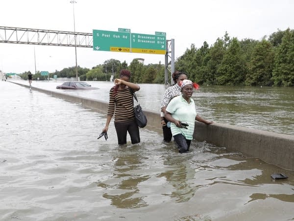 Evacuees wade down a flooded Interstate 610