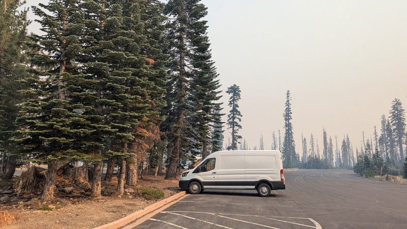 Our cargo van parked alone in a parking lot with hazy smoke obscuring the view behind