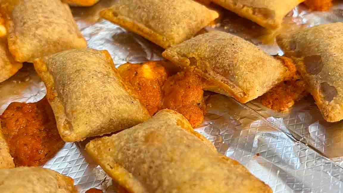 Closeup of fully-cooked Totino's pizza rolls with the fillings leaking out