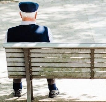 person sitting on beige street bench near trees