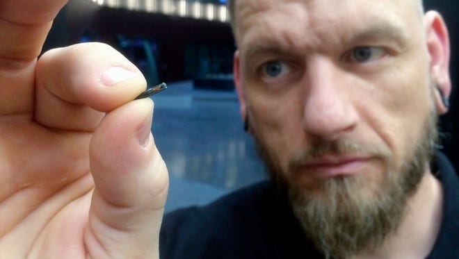 Jowan Osterlund from Biohax Sweden holds a small microchip implant, similar to those implanted into workers at the Epicenter digital innovation business center during a party at the co-working space in central Stockholm. Three Square Market in River Falls, Wis., is partnering with Sweden's BioHax International, offering to microchip its employees, enabling them to open doors, log onto their computers and purchase break room snacks with a simple swipe of the hand. More than 50 employees are voluntarily getting implants Aug. 1 at what the company is calling a "chip party" at its River Falls headquarters.