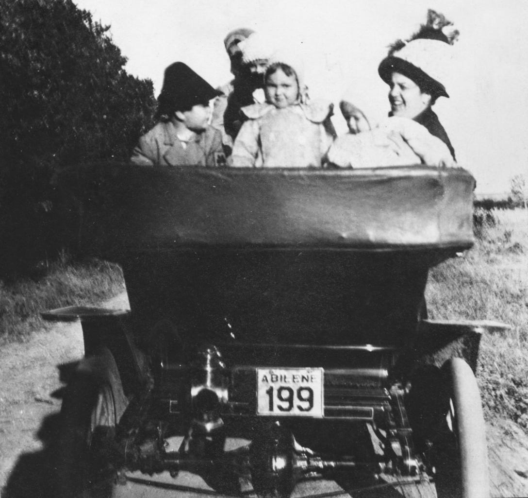 Family in the back of a car in the early 1900s, license plate reads "Abilene 199"