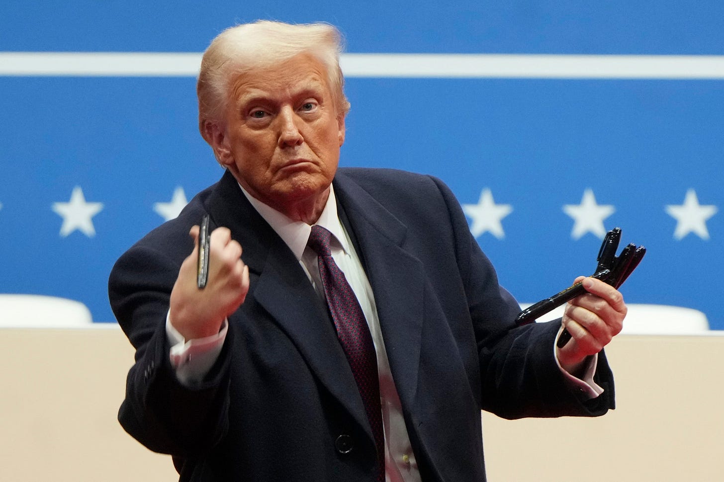 President Donald Trump throws pens used to sign executive orders to the crowd during an indoor Presidential Inauguration parade event in Washington