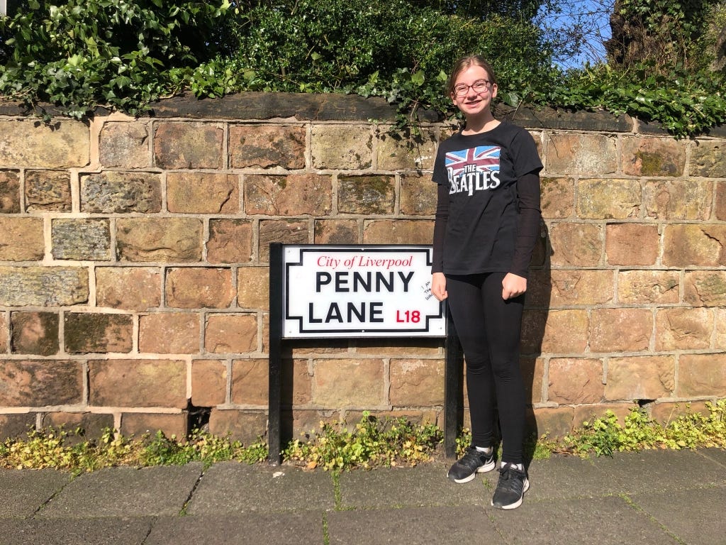 Molly stands next to the City of Liverpool Penny Lane sign