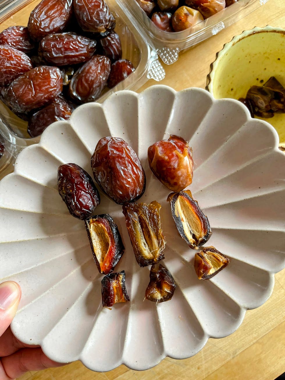Hand holding a plate of three different types of dates and their cross sections