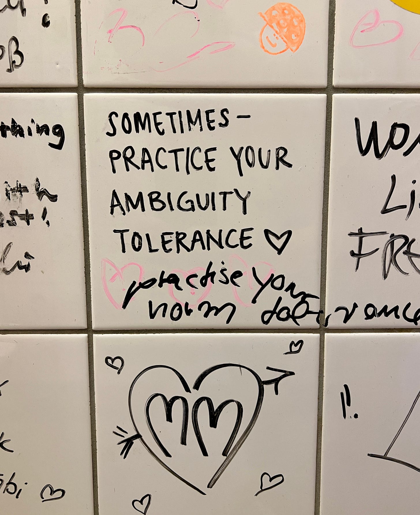 Bathroom tile with graffiti that reads "sometimes practice your ambiguity"