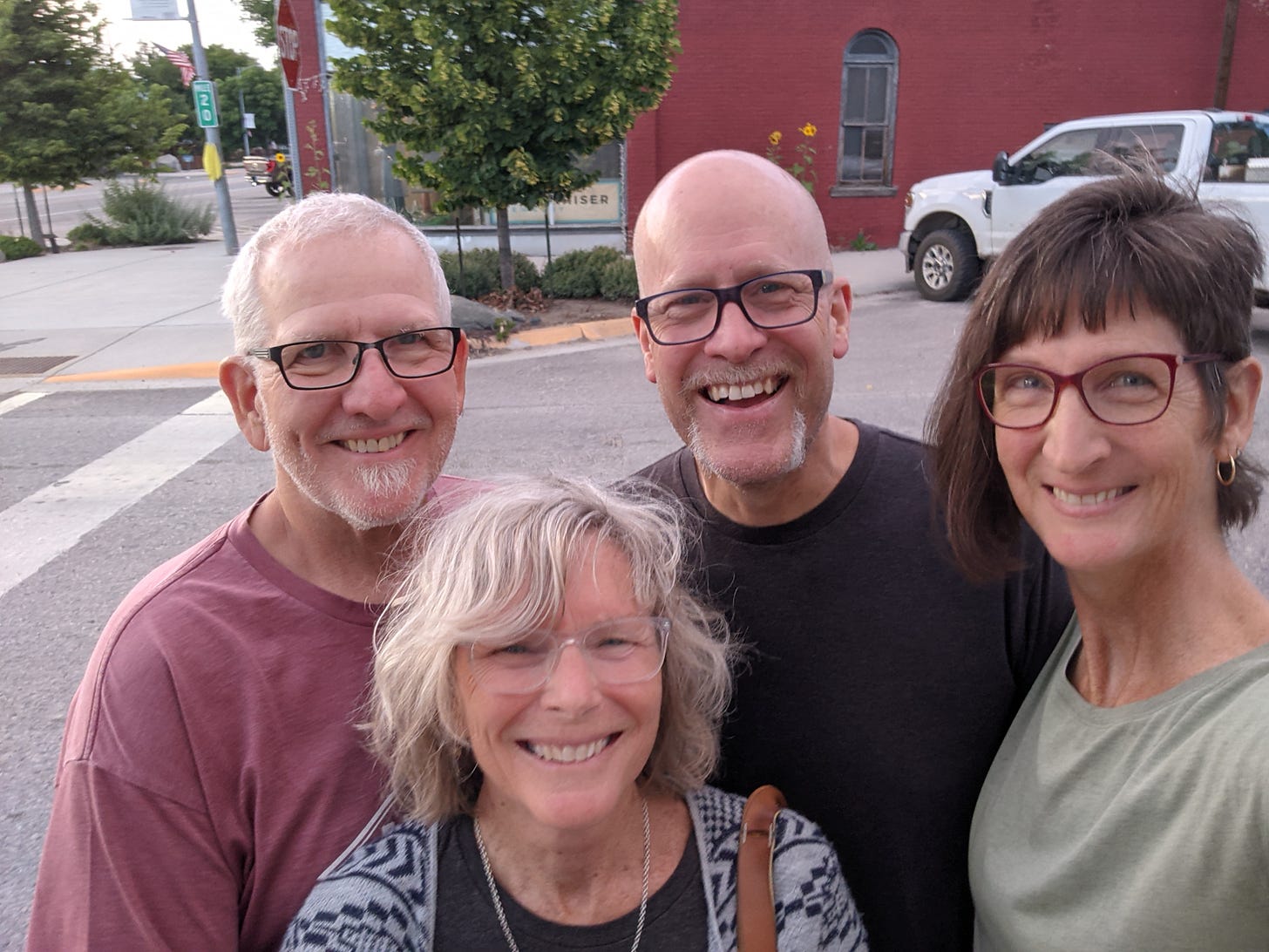 Four people, two couples, smiling at the camera with a small town in the background