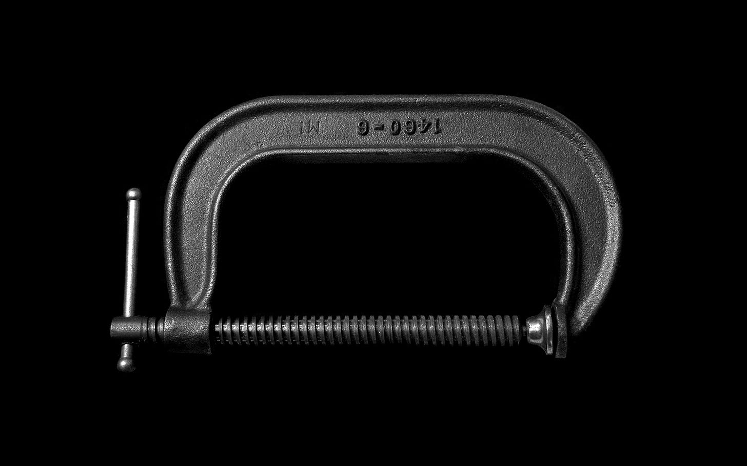 Serious portrait of a metal C clamp on a black background