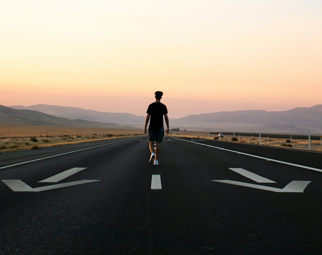 man in black jacket and black pants standing on black asphalt road during daytime man in black jacket and black pants standing on black asphalt road during daytime