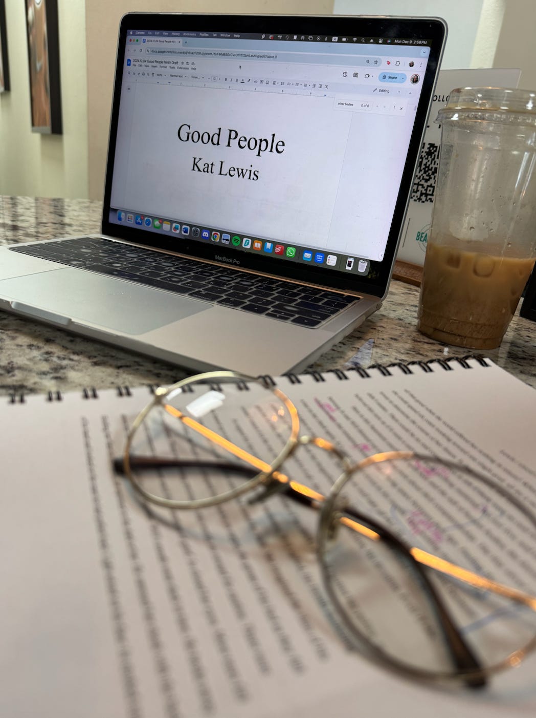 A photo of Kat's marked up, printed manuscript and her laptop opened to the title page of her novel, GOOD PEOPLE.