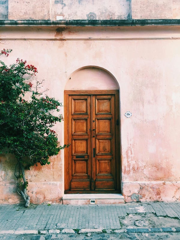 Brown door, with a tree beside it. Brown door, with a tree beside it.