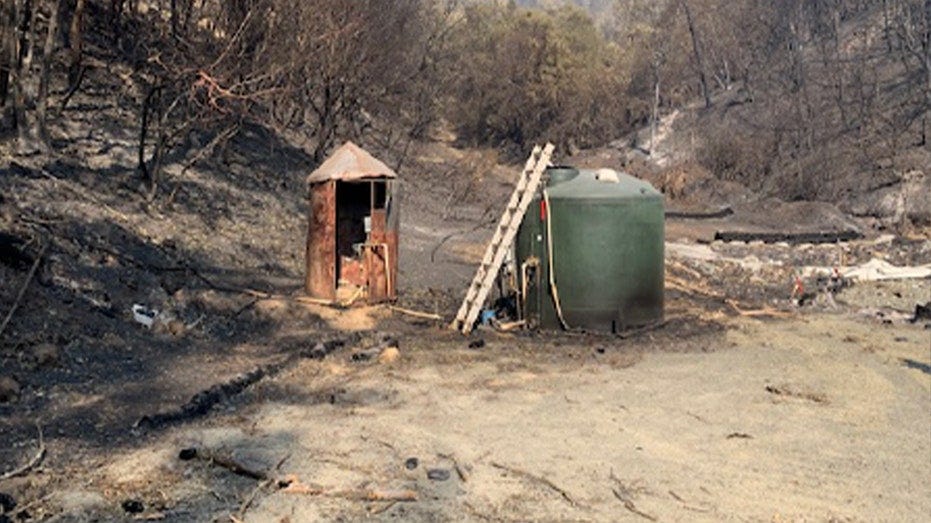 Fire-damaged pump house at landfill seen amid burned brush and trees