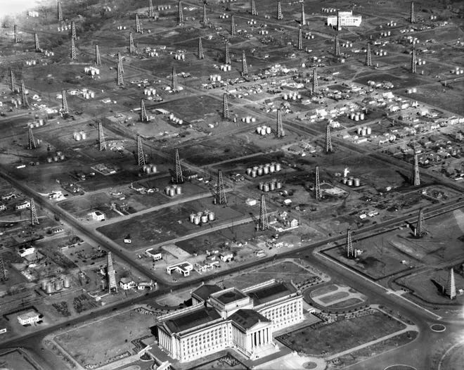 Aerial photo shows the Oklahoma State Capitol Building (center foreground) and looks northeast across a forest of oil drilling rigs and storage tank farms towards Northeast High School at NE 31 and Kelley (upper right corner). The Daily Oklahoman, staff photo taken 2/9/1938.