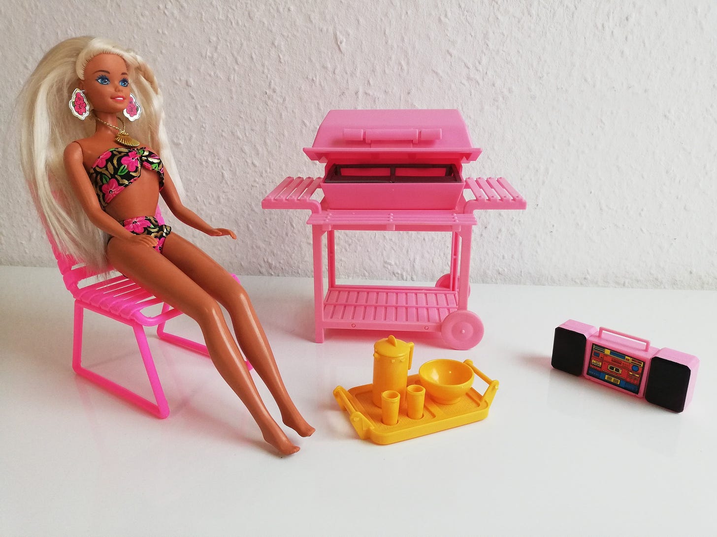 Display of a Barbie doll next to a pink grill. 
