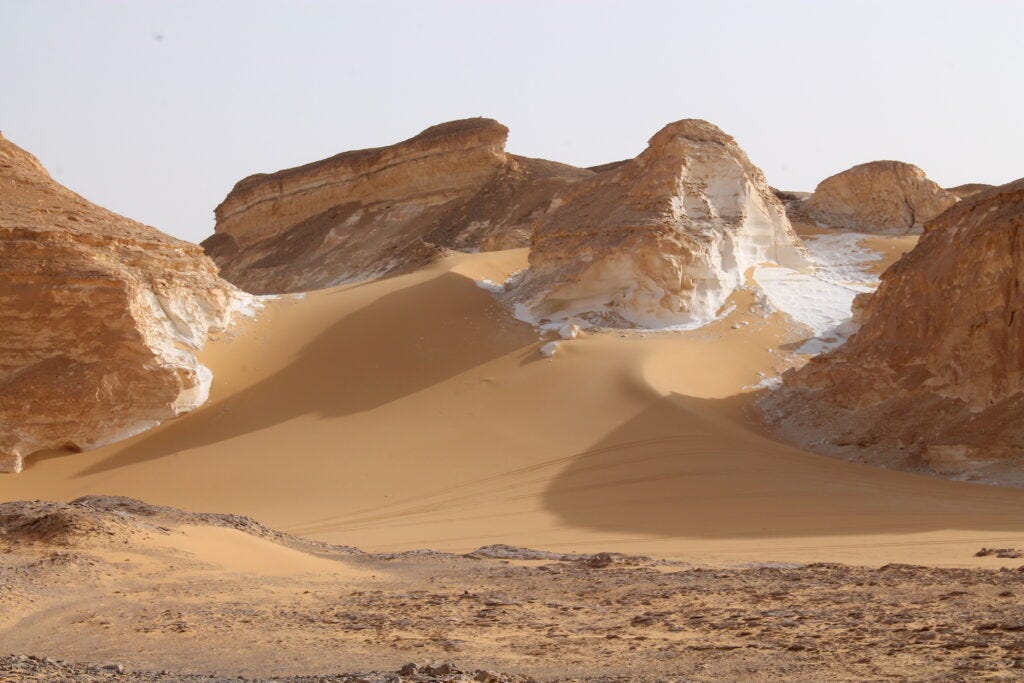 White and taupe mountains in the Agabat Valley above the sand.