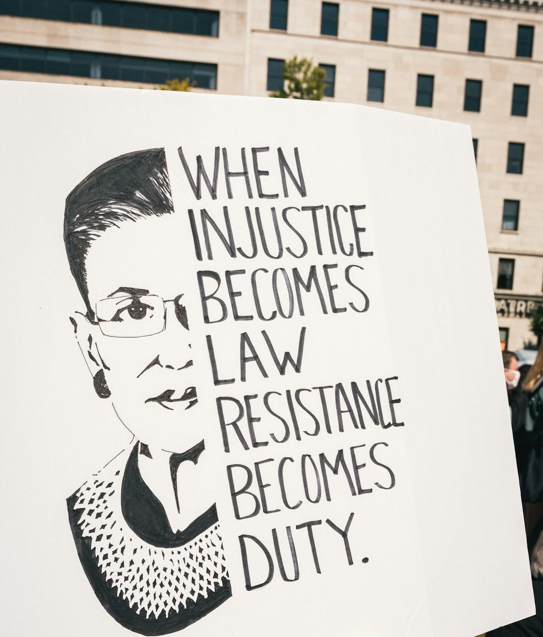 a person holding a sign that says when justice becomes law, resistance becomes duty