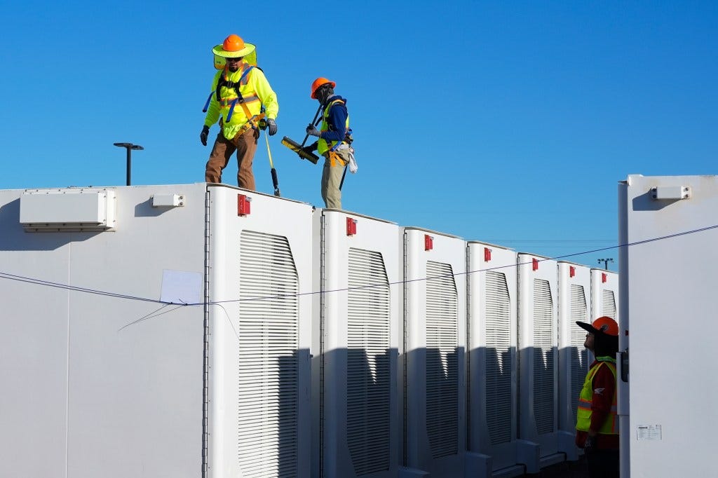 Workers inspecting battery storage pods at Orsted's Eleven Mile Solar Center lithium-ion battery storage energy facility in Coolidge, Ariz.