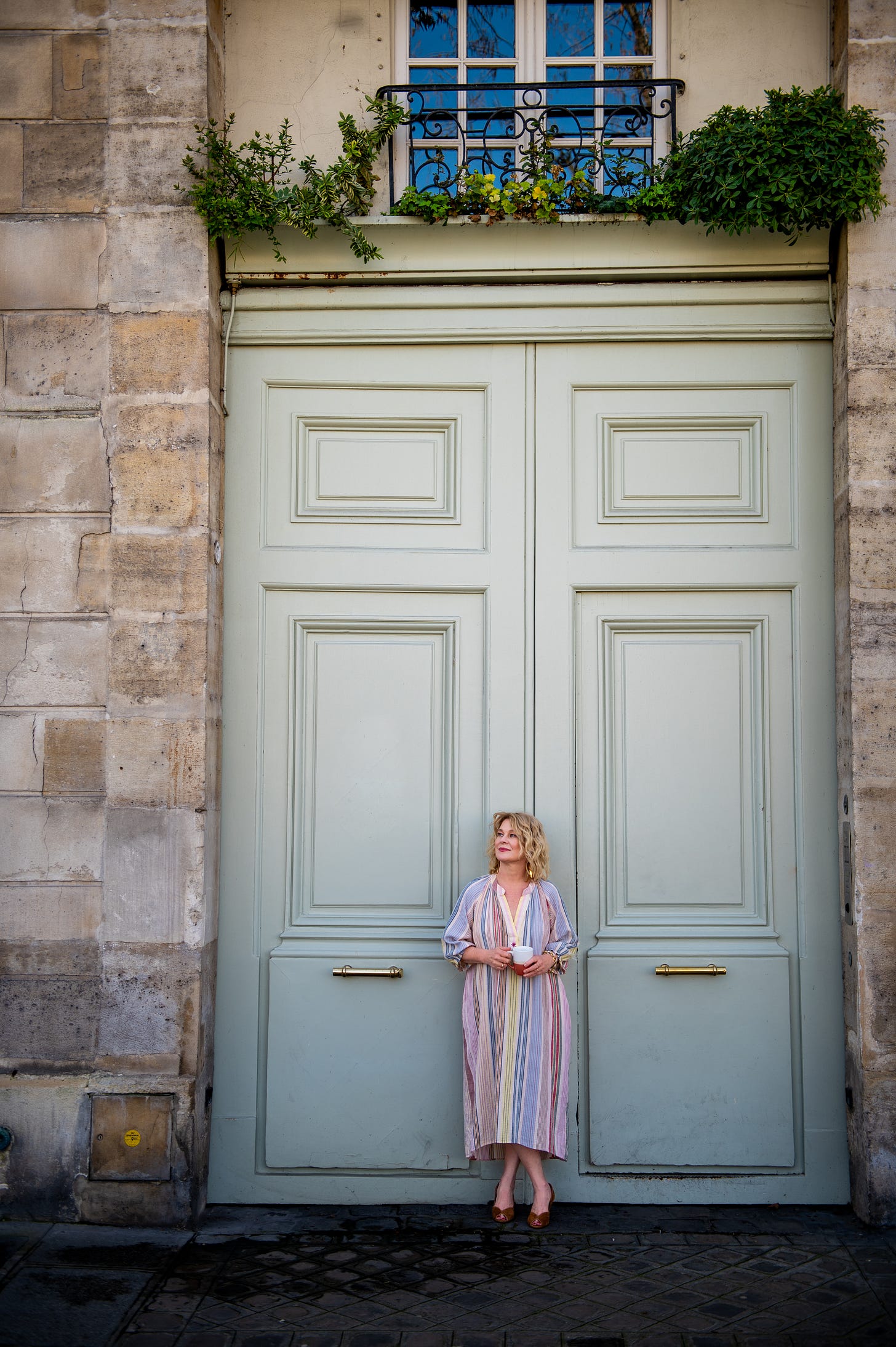 Karen Bussen stands in front of a pale green Parisian door