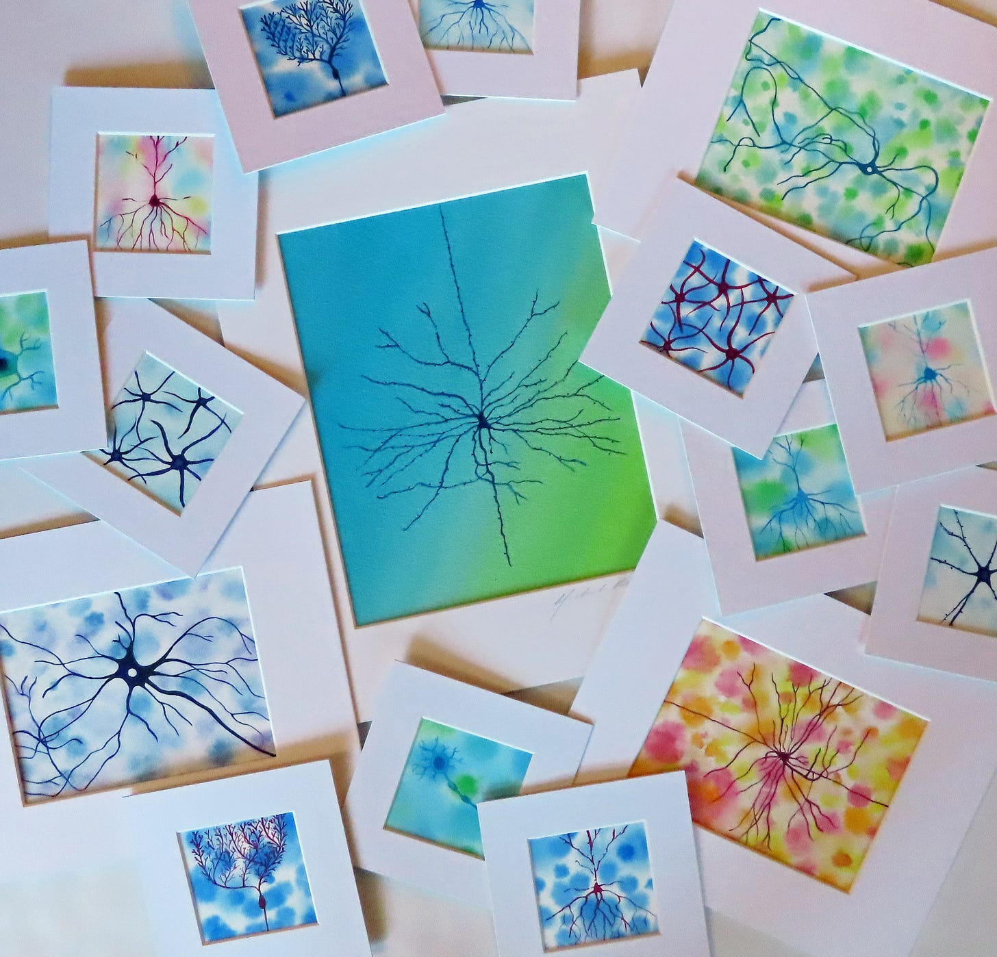watercolor neuron paintings spread on a table