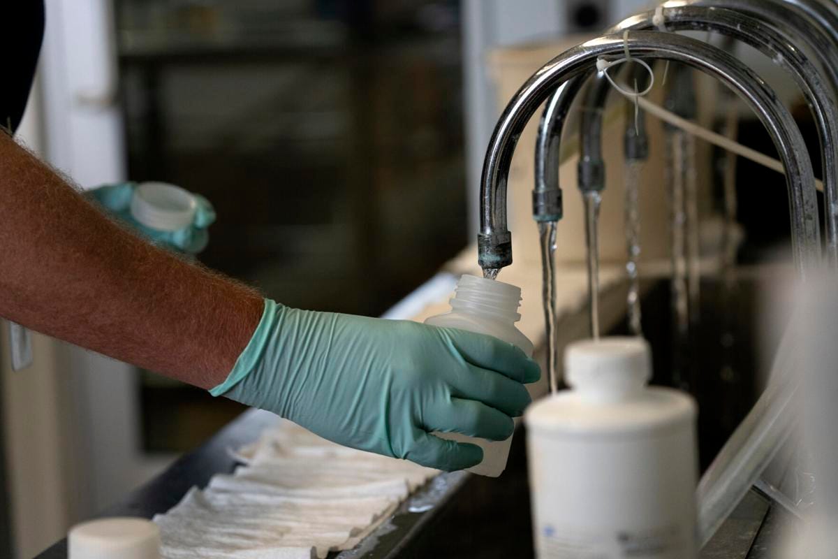 An Illinois Environmental Protection Agency geologist collects samples of treated Lake Michigan water in a laboratory at the Wilmette water treatment plant on July 3, 2021.