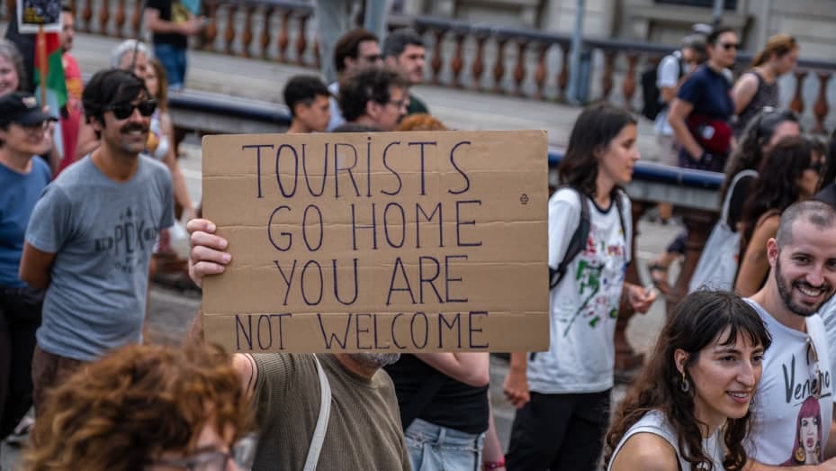 BARCELONA, CATALONIA, SPAIN - 2024/07/06: An anti-tourism placard is seen during the demonstration. More than 3,000 people demonstrated against the tourist overcrowding suffered by the city of Barcelona and in favor of tourism reduction policies. The demonstration involved symbolically closing hotel establishments, bars and restaurants while heading towards Barceloneta, one of the neighborhoods that suffers the most from the presence of tourism. (Photo by Paco Freire/SOPA Images/LightRocket via Getty Images