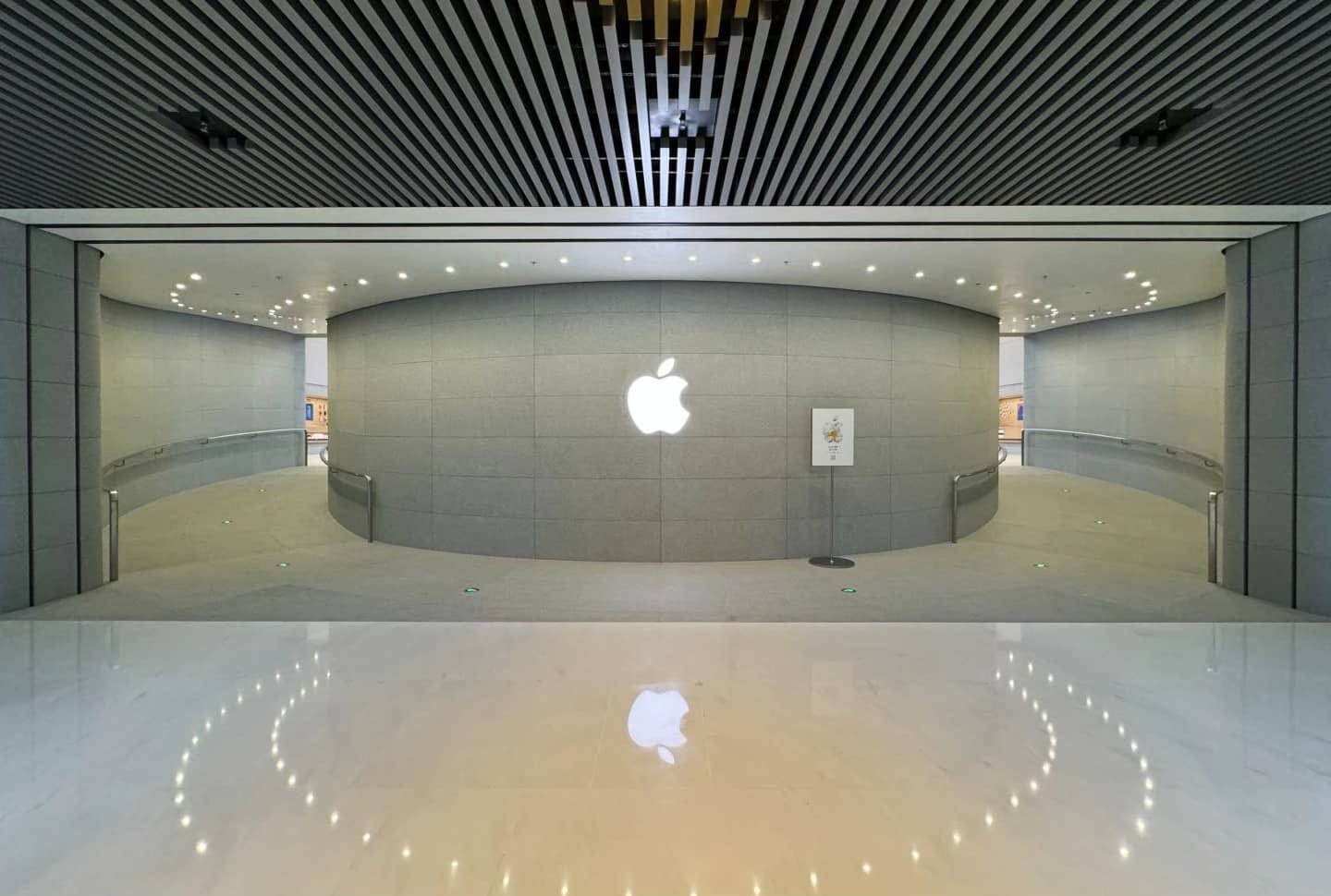 The entrance to Apple Jing'an from the Shanghai Metro. A curved wall splits foot traffic in two directions. Ramps lead into the store.