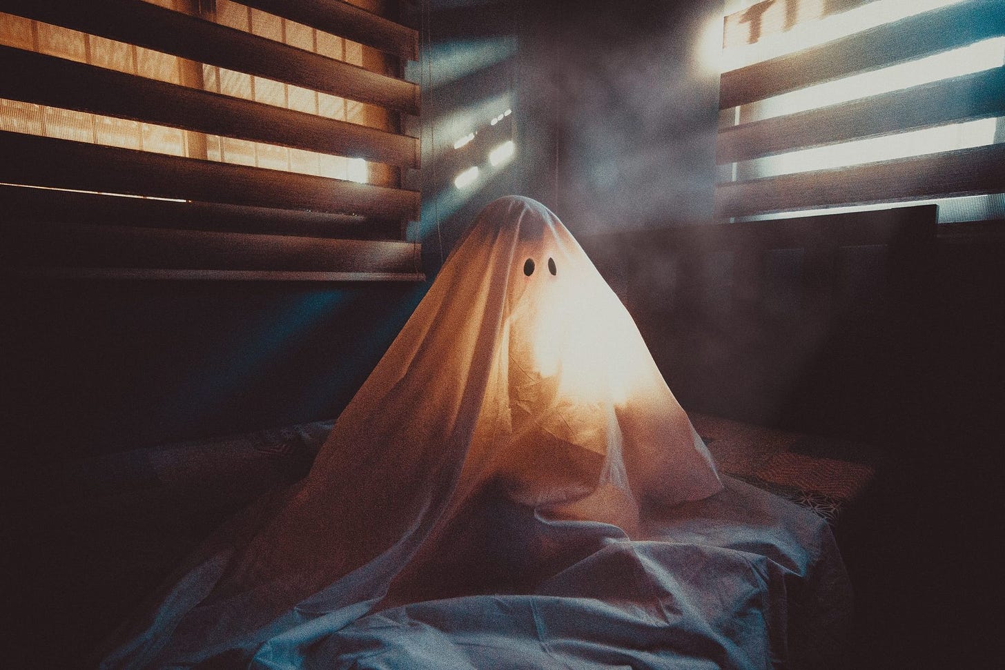 ghost hiding under a blanket in a dark room