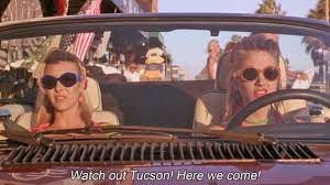 Screenshot of Romy & Michele in their Jaguar convertible, their hair in cute scarves and sunglasses over their eyes, as they say "Watch out Tucson! Here we come!"