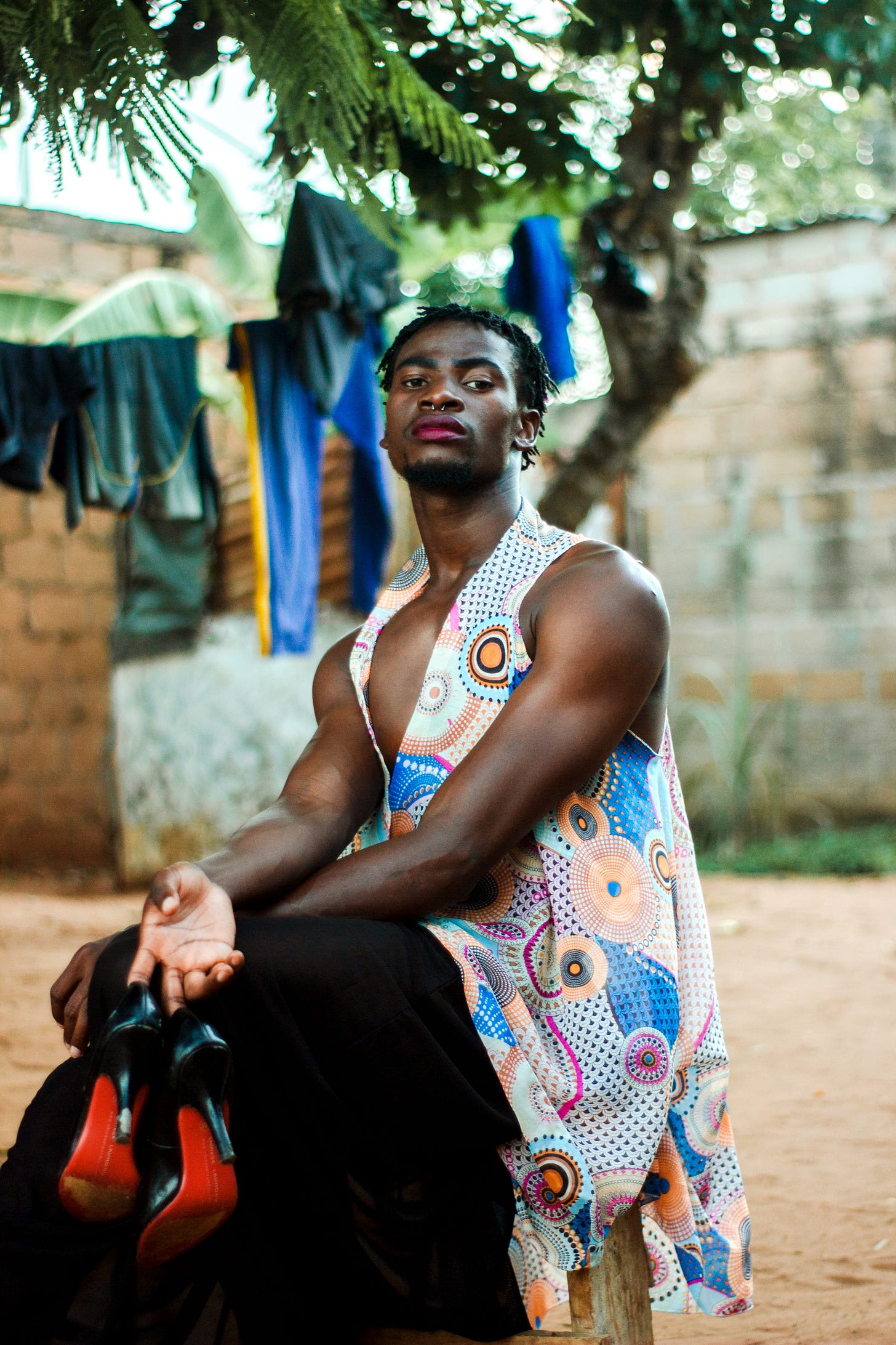 A masc person holding a pair of heels
