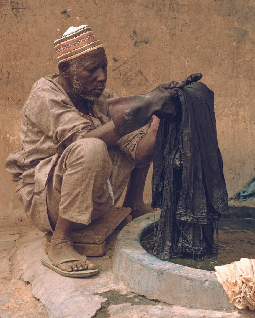 A man dyeing a fabric with indigo dye at Kofar Mata Dye Pit, image by Samuel Tadafe 2021