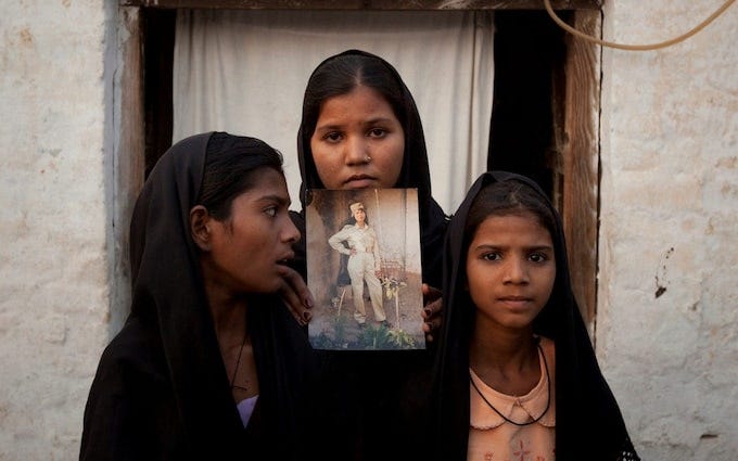 The daughters of Pakistani Christian woman Asia Bibi pose with an image of their mother while standing outside their residence in Sheikhupura Pakistan