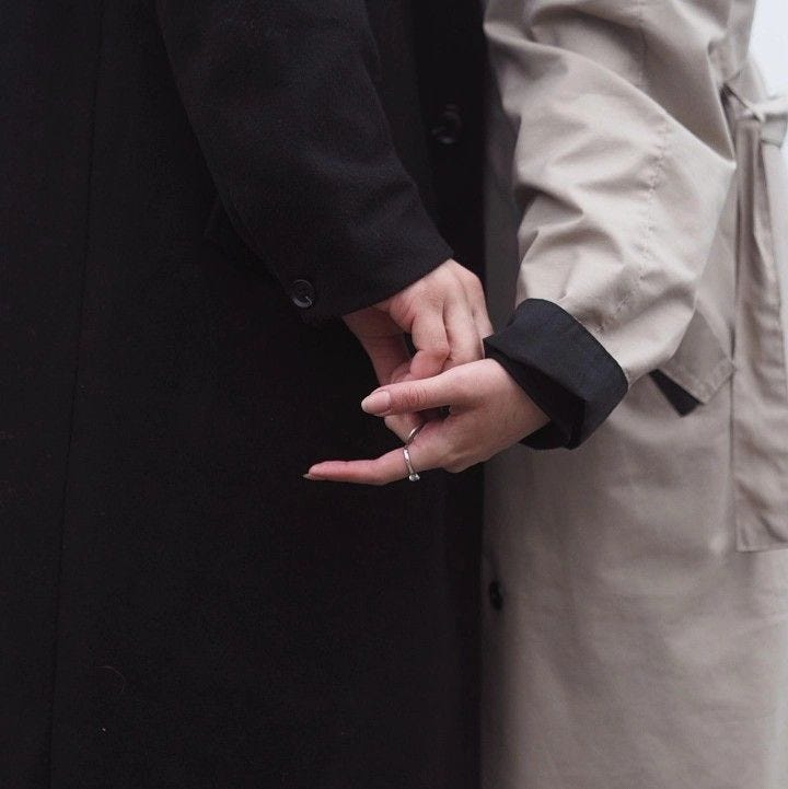 This may contain: two people standing next to each other with their hands on one another's fingers