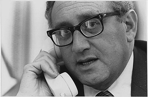 Kissinger wearing a suit and holding a phone in a black and white picyure