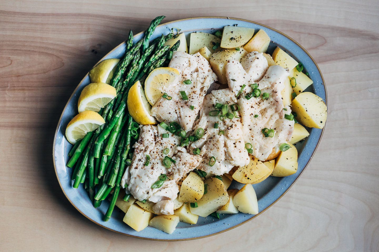 A platter with potatoes, cod, and asparagus