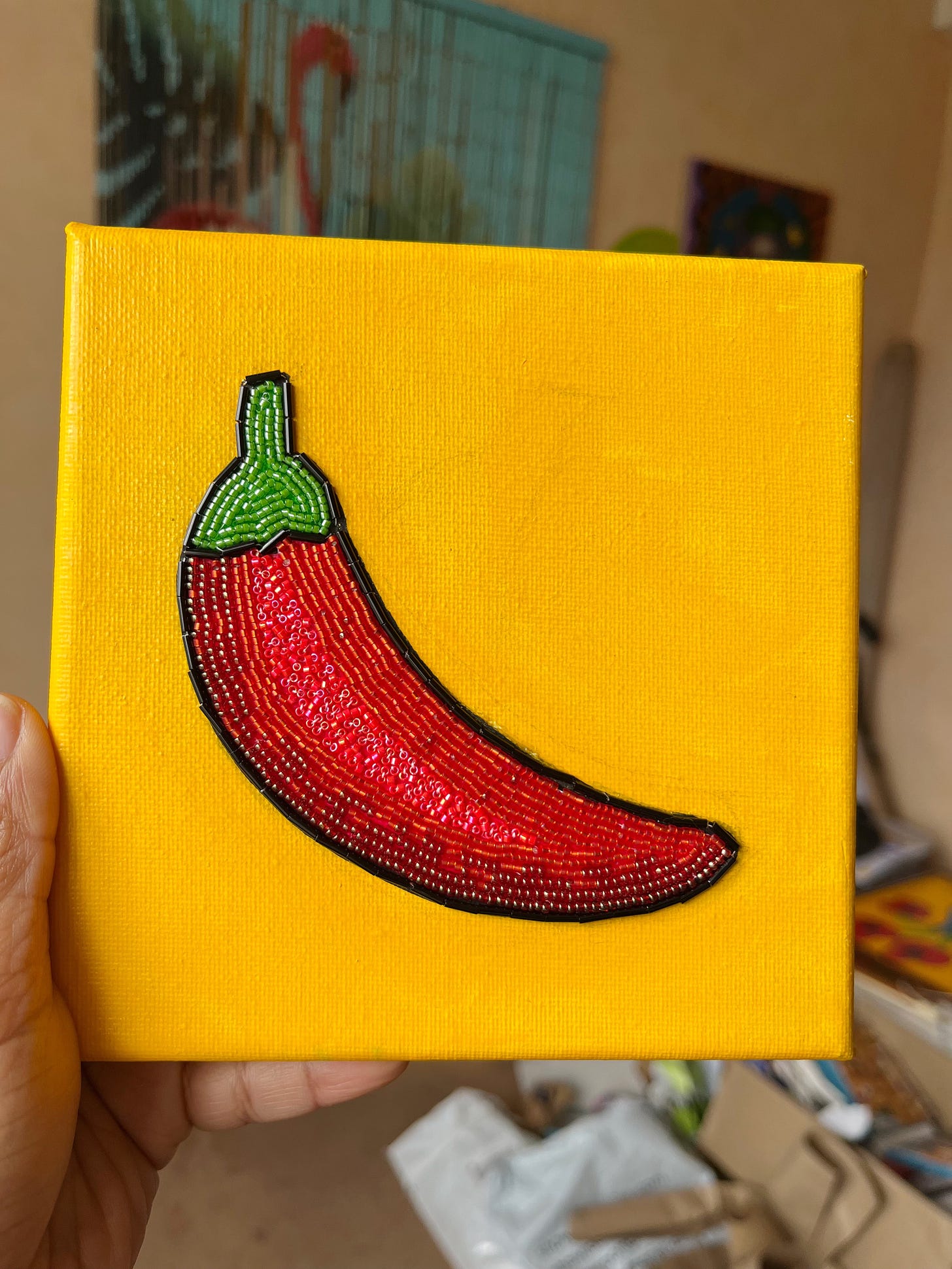 A painting of a red chili with beads